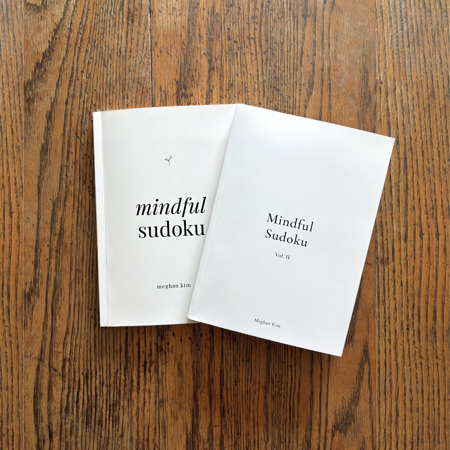 The Mindful Sudoku Original journal and Volume II paperbacks side by side on a wooden table